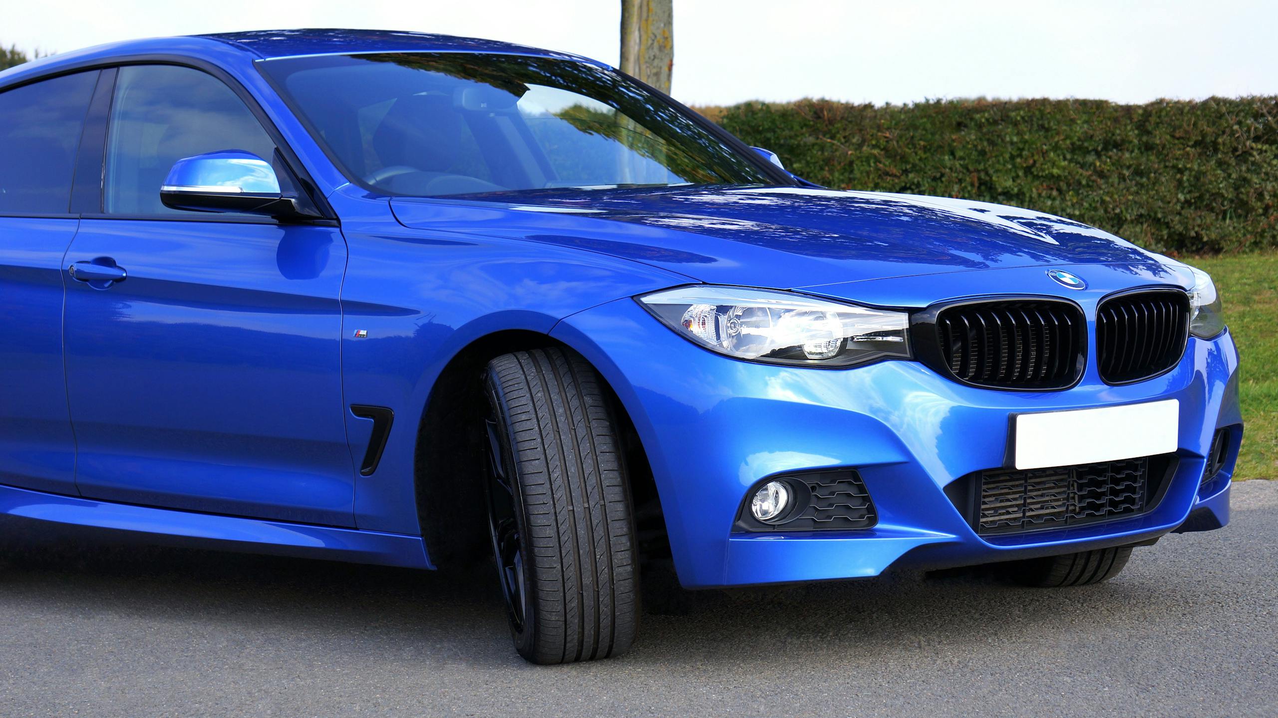 Close-up of a shiny blue luxury sedan parked outdoors, showcasing modern design and performance.